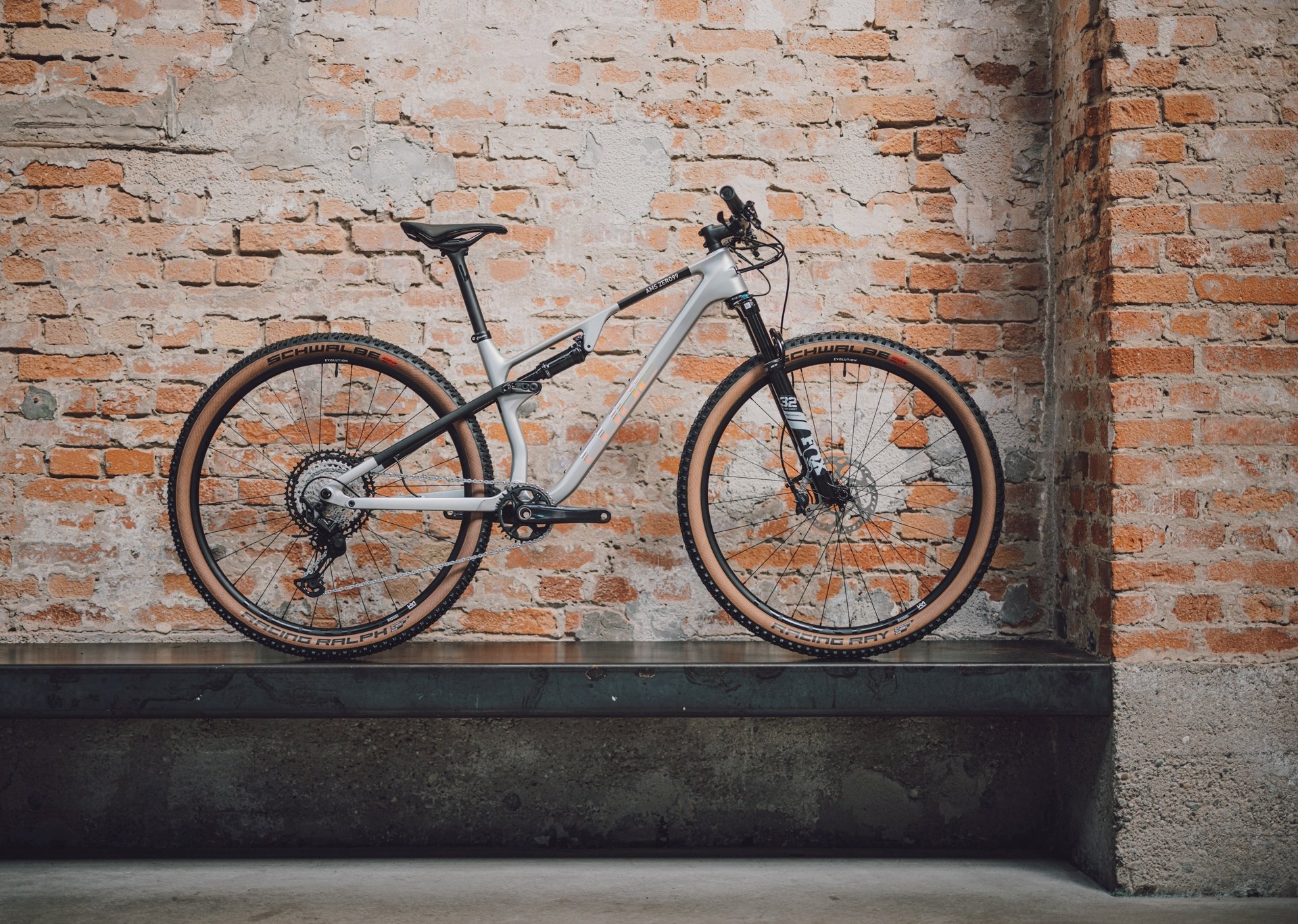 En modern Cykel står elegant mot en rustik tegelvägg. Mjukt, diffust ljus framhäver detaljerna på både cykeln och bakgrunden, vilket skapar en avslappnad och stilren atmosfär.